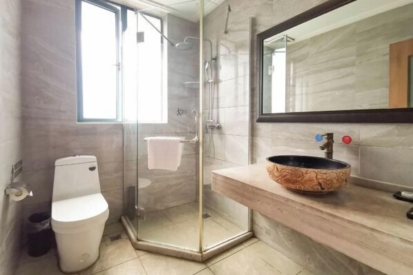 A bathroom with a glass-enclosed shower, a white toilet, and a wooden vanity with a bowl sink. - Yuan Jin Inn (Hangzhou)
