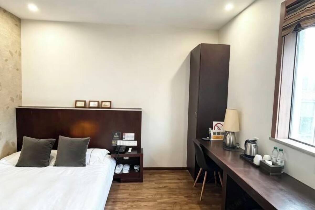 Ein Hotelzimmer mit Bett, Schreibtisch, Kleiderschrank und Fenster.