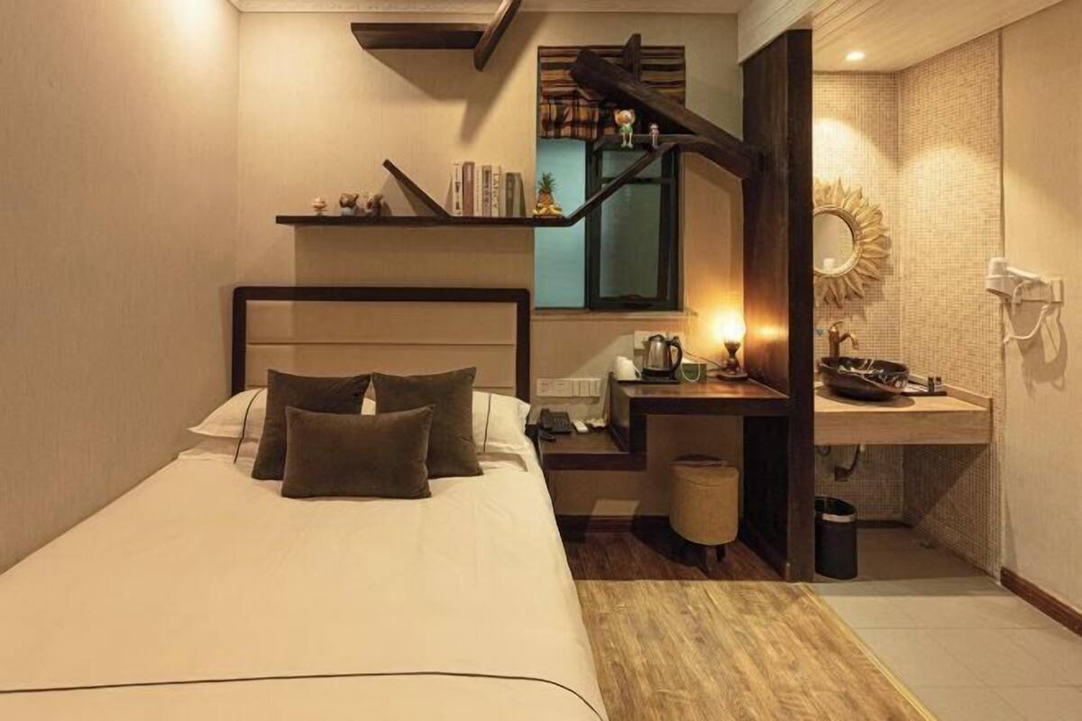 Ein modernes Hotelzimmer mit einem Bett, einer Holztreppe, einem Schminktisch mit Spiegel und einem kleinen Tisch mit Lampe.