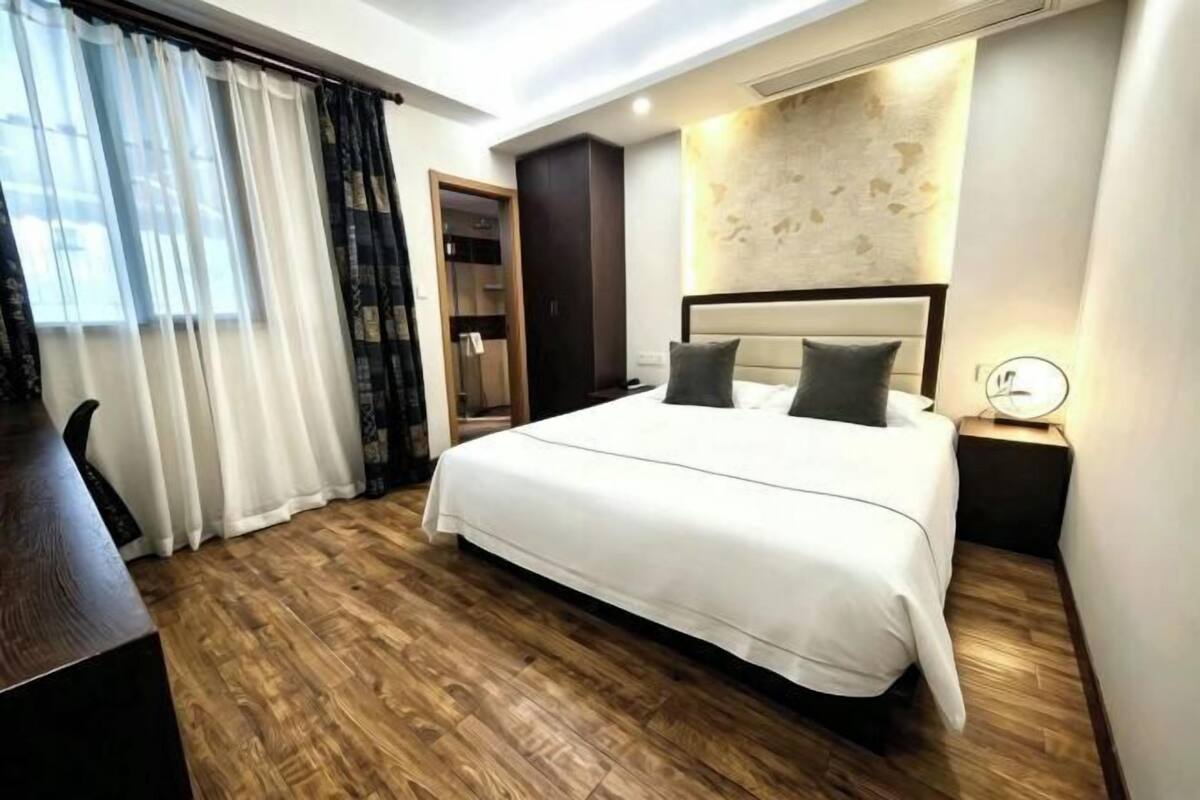 Ein Hotelzimmer mit einem großen Bett, einem Schreibtisch, einem Kleiderschrank und einem Spiegel.