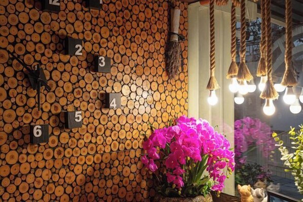 A wall of stacked logs with numbered sections, a mirror reflecting the room, and hanging light fixtures. - Yuan Jin Inn (Hangzhou)