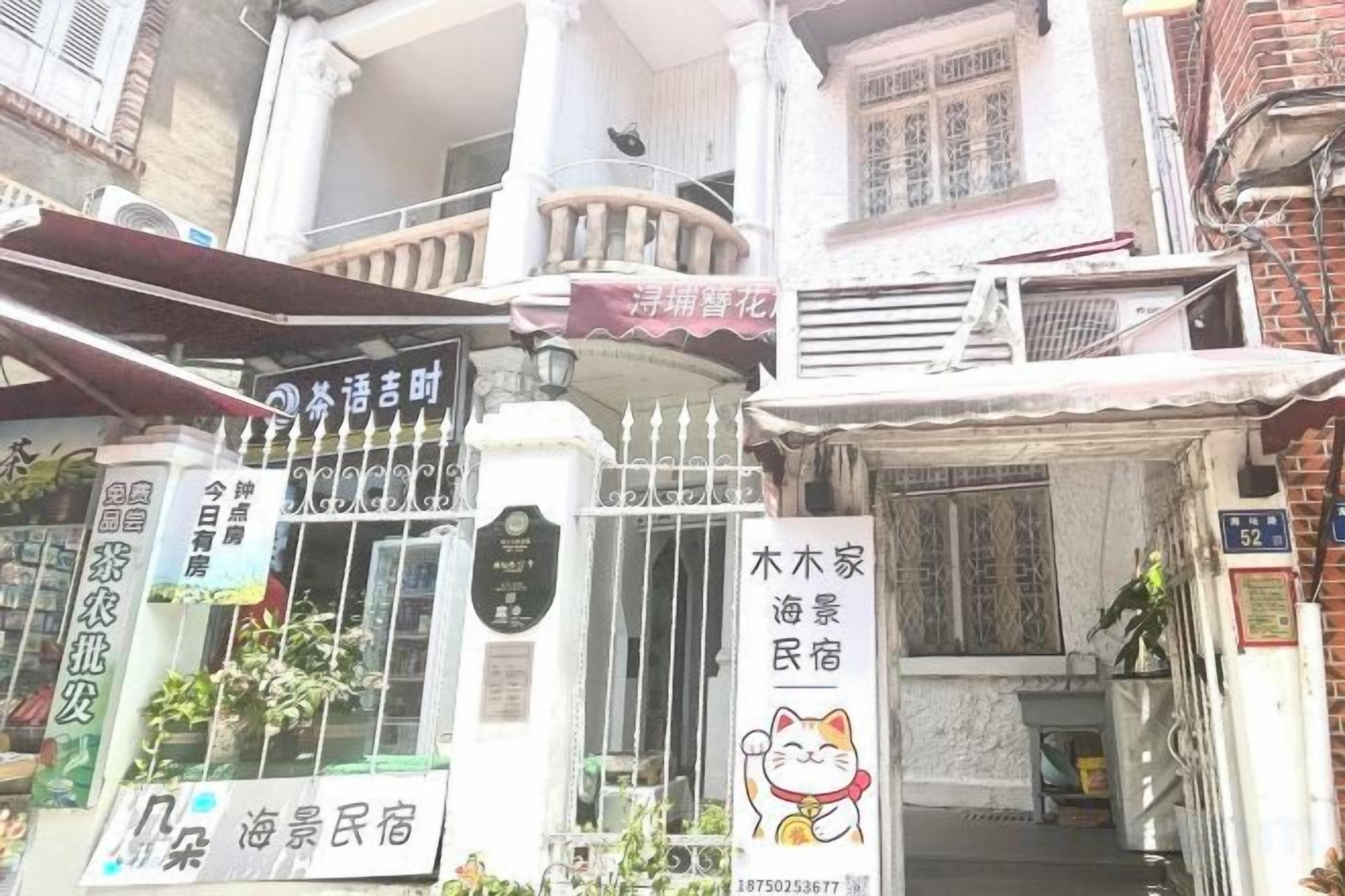 A traditional building with a gated entrance, a balcony, and multiple signs indicating various businesses.