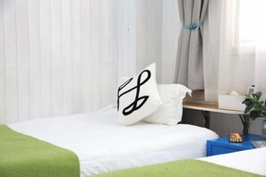 A neatly made bed with a white bedspread, a green throw blanket, and a decorative pillow with a black design. - Mumujia Homestay (Xiamen)