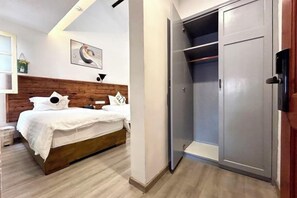 Une chambre à coucher avec un lit, une tête de lit en bois, une armoire et un tableau accroché au mur.