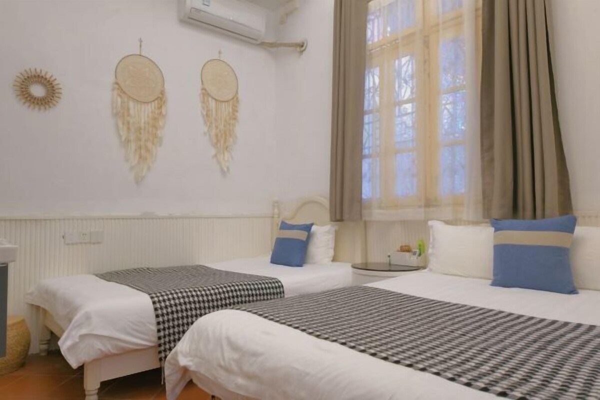 A bedroom with two beds, a window with curtains, and wall decorations.