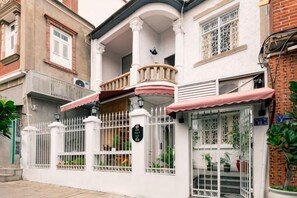 A two-story building with a balcony, a gated entrance, and a window with a view of the street. - Mumujia Homestay (Xiamen)