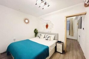 A bedroom with a bed, bedside table, and a wall-mounted light fixture. - Mumujia Homestay (Xiamen)