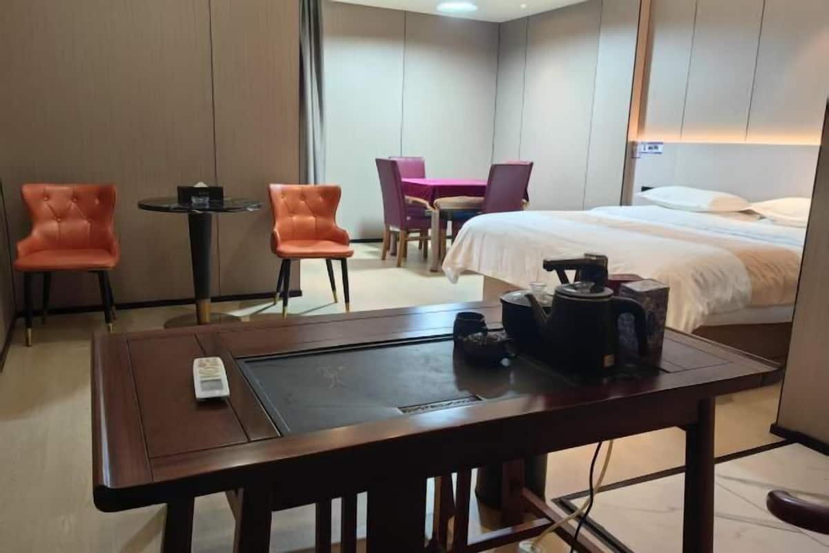 A hotel room with a bed, a desk with a chair, a small table, and a separate dining area with a table and chairs.