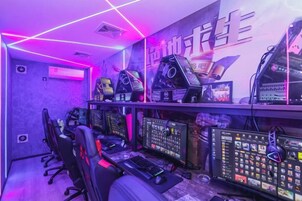 Una sala de juegos con varias estaciones de juego, sillas y una pantalla grande.