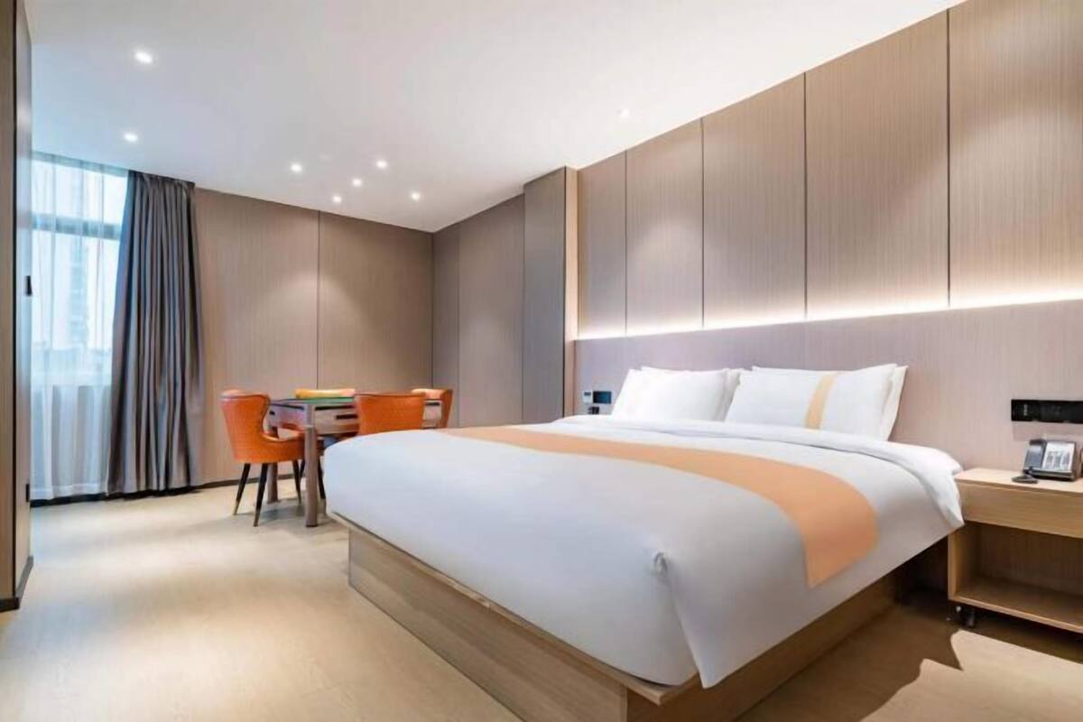 A modern hotel room with a large bed, a desk, and a chair.