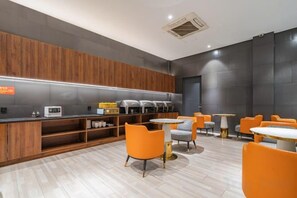 A modern kitchen area with a coffee station, seating area with orange chairs, and a counter with appliances. - Kairui Meisu Hotel (Taizhou Zhongsheng Plaza store) (Taizhou)