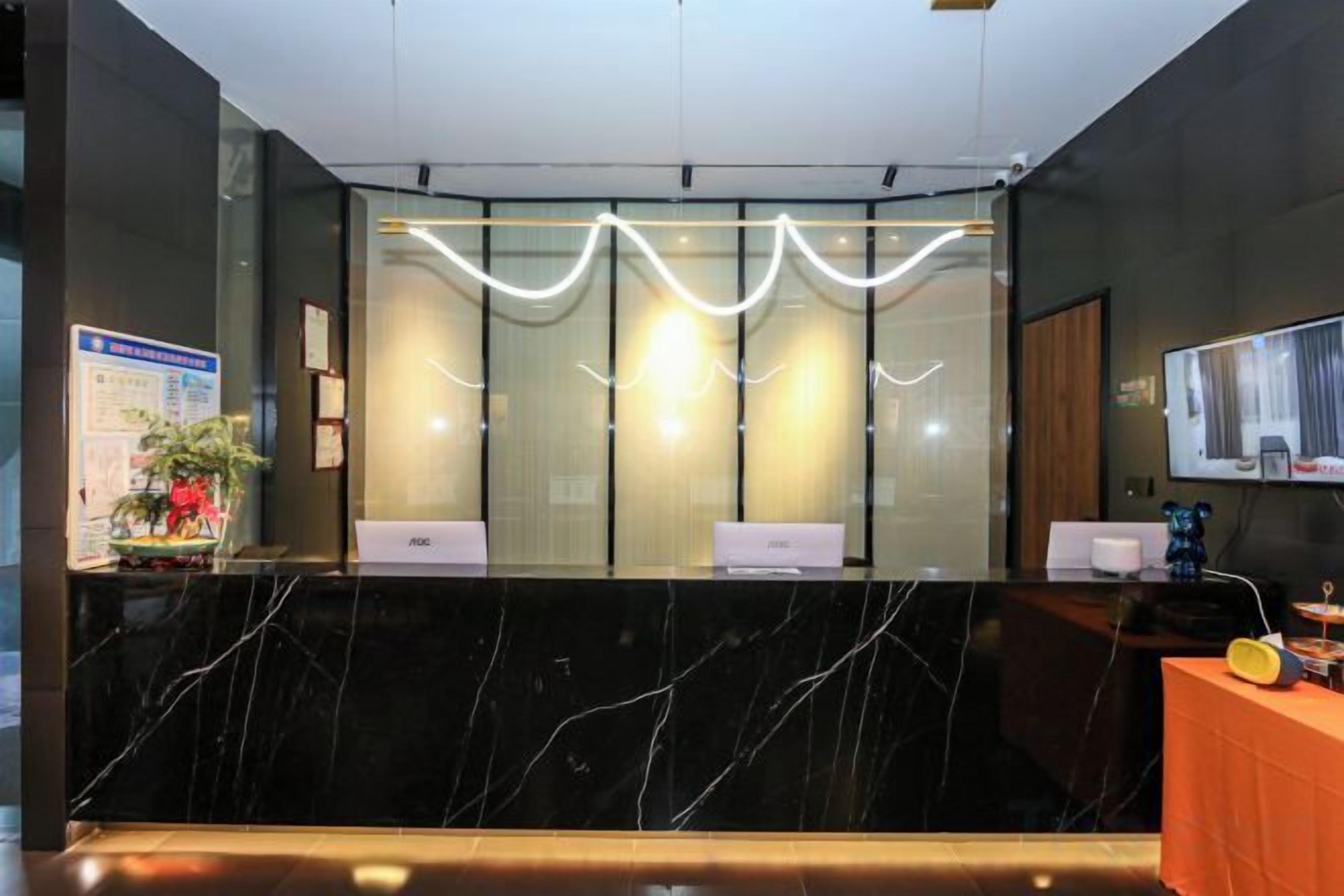 A reception desk with a marble countertop, a glass partition, and a modern light fixture above.
