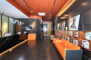 Eine Hotlellobby mit einer Rezeption, einer Sitzecke und einer Wand mit gerahmten Bildern.