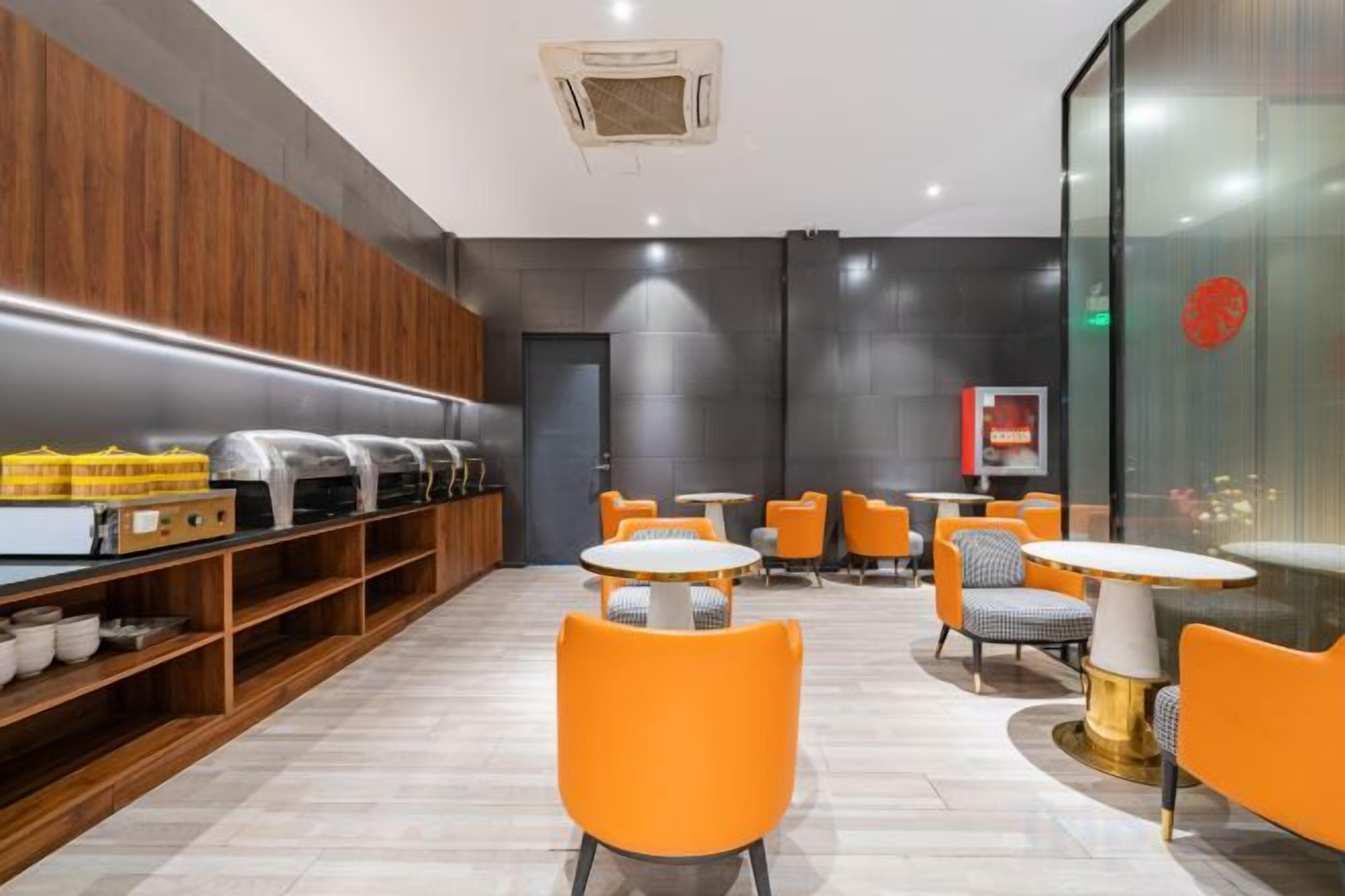 A modern interior with a seating area, a counter with food items, and a wall with a logo.