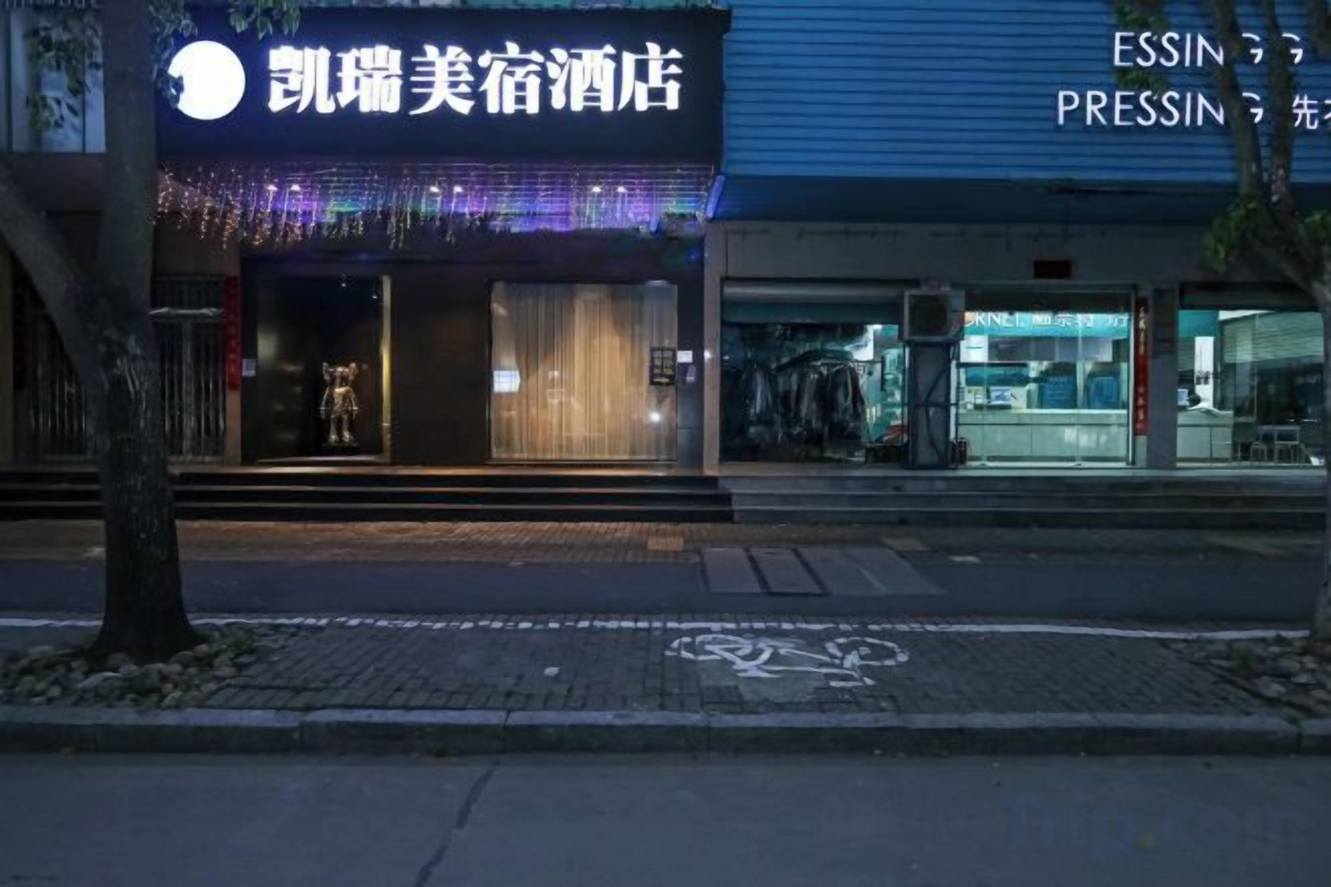 A hotel entrance with a sign, a visible entrance, and a street in front.