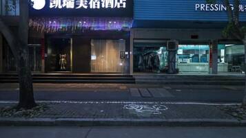 A hotel entrance with a sign, a visible entrance, and a street in front.