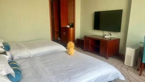 Una habitación de hotel con dos camas, un televisor, un armario de madera y una mesita pequeña.