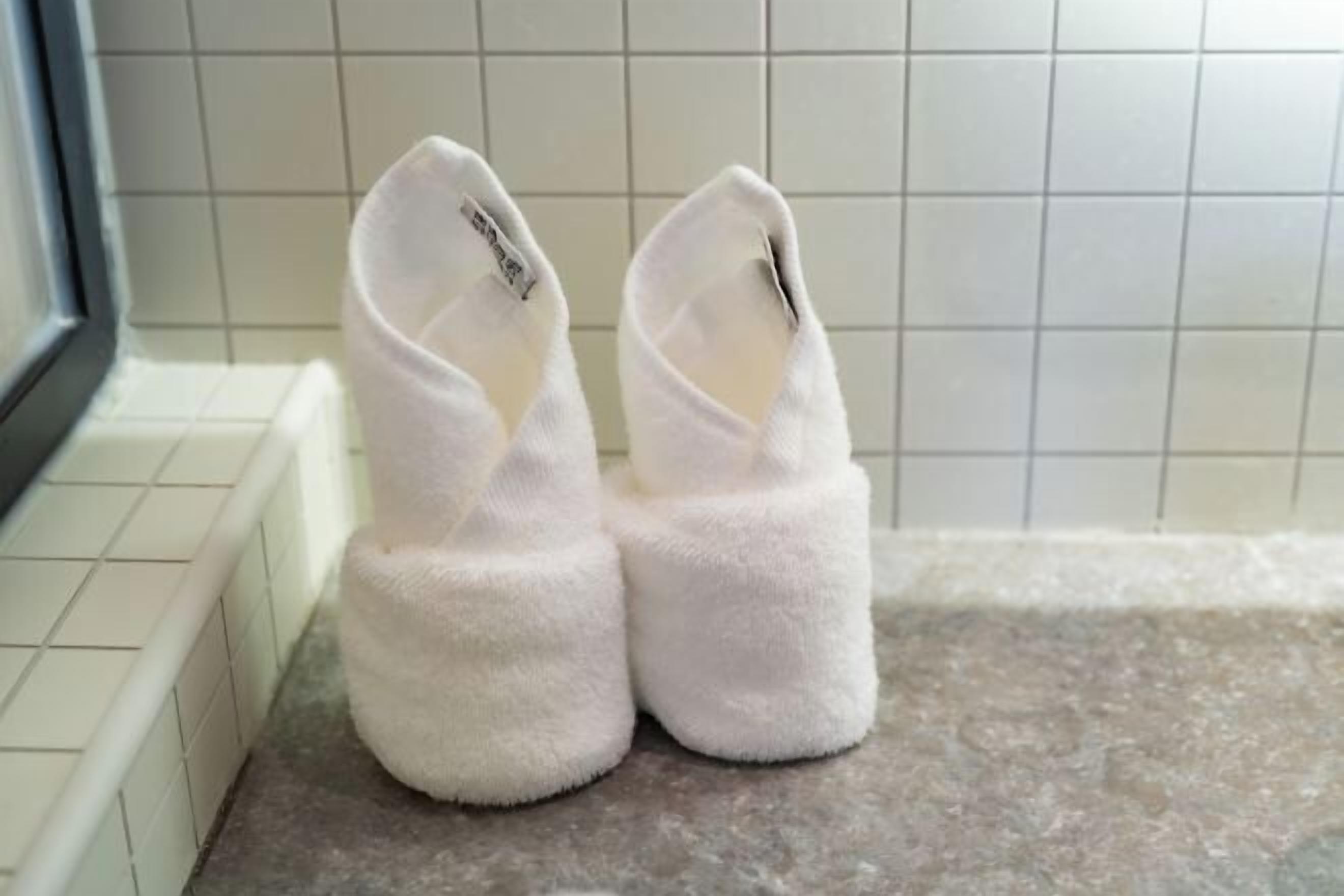 A pair of white slippers on a tiled floor.