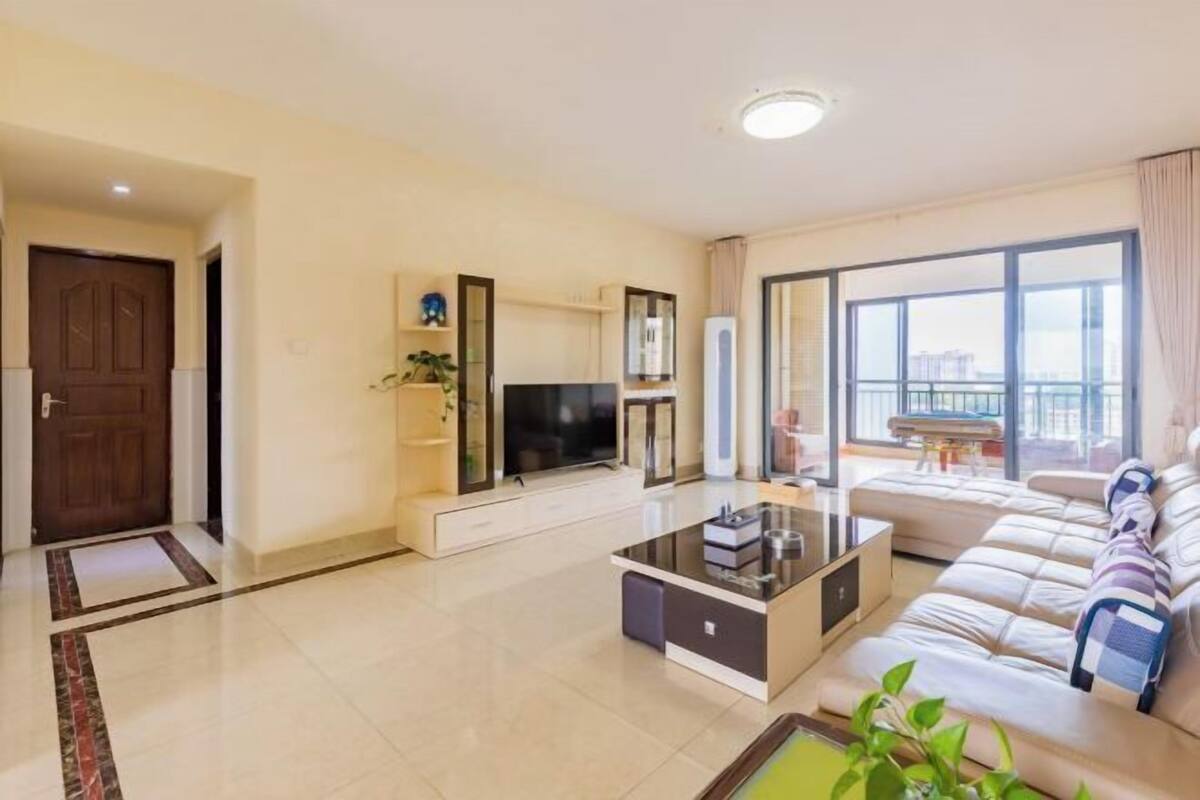 Een moderne woonkamer met een bank, een salontafel, een televisie en een balkon met uitzicht.