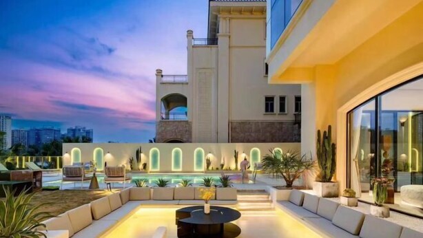 An outdoor lounge area with a pool, seating, and a modern building in the background.