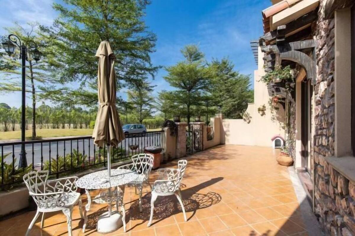 Een terras buiten met een tafel en stoelen, een overdekte parasol en een stenen muur.