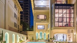 A multi-story hotel with a pool, balconies, and a well-lit interior.