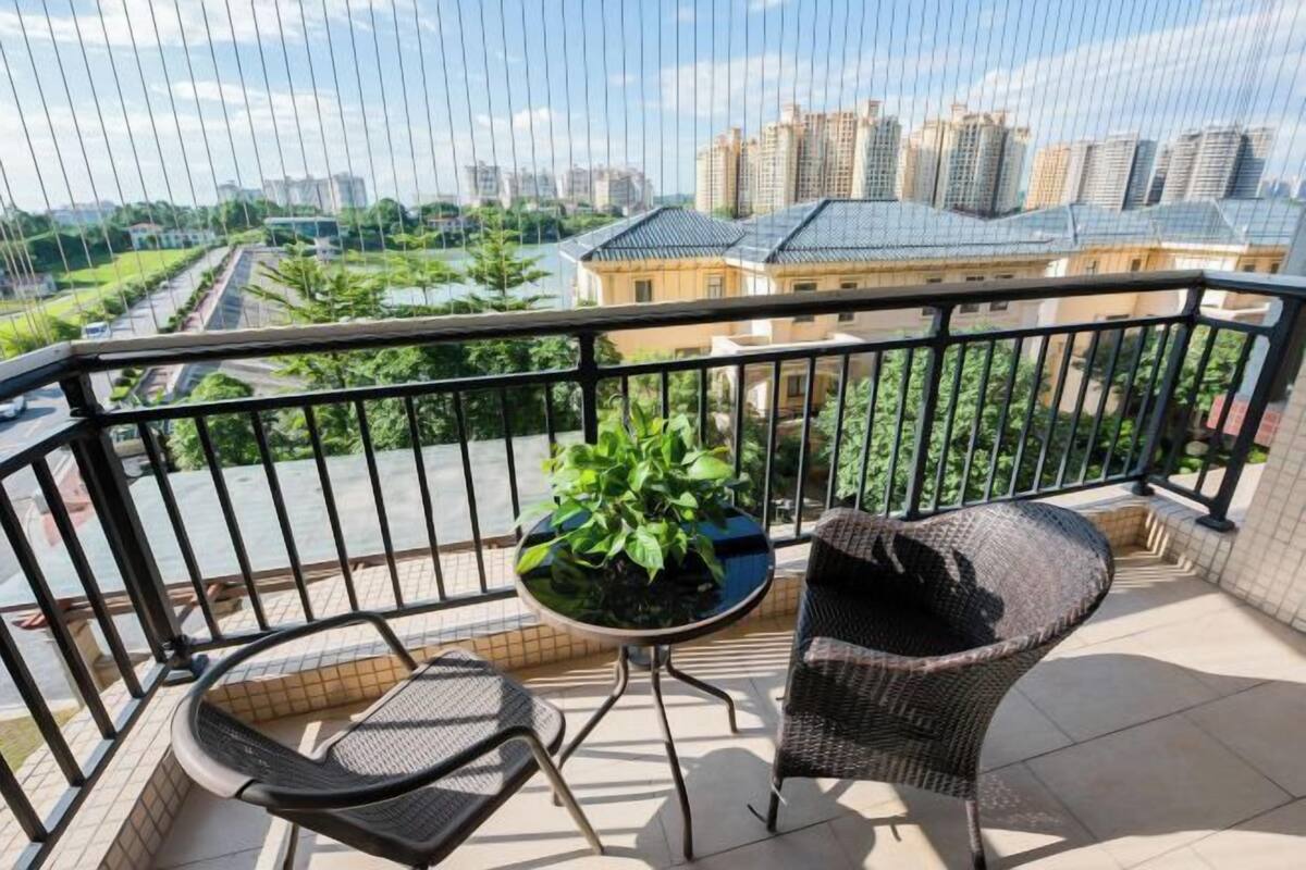Een balkon met uitzicht op een stadsbeeld, een bloempot en twee rieten stoelen.