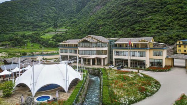 Un hôtel doté d’une piscine, d’une structure blanche en forme de tente et traversé par une rivière.