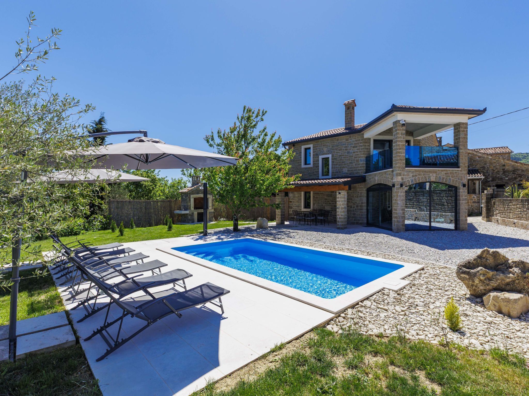 Ein zweistöckiges Steinhaus mit Swimmingpool, Außenbereich und überdachter Terrasse.