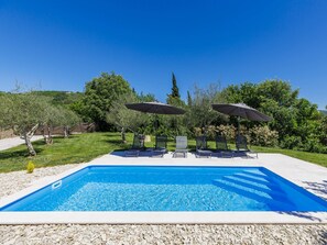 A swimming pool with lounge chairs and umbrellas, surrounded by greenery and hills. - Solaria by Interhome (Motovun)