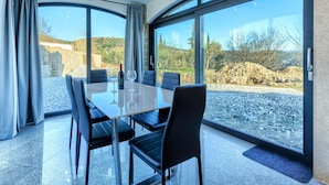 A modern dining area with a glass table, black chairs, and a scenic view through large windows.