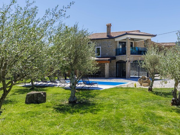 A two-story stone house with a swimming pool, outdoor seating, and olive trees. - Solaria by Interhome (Motovun)