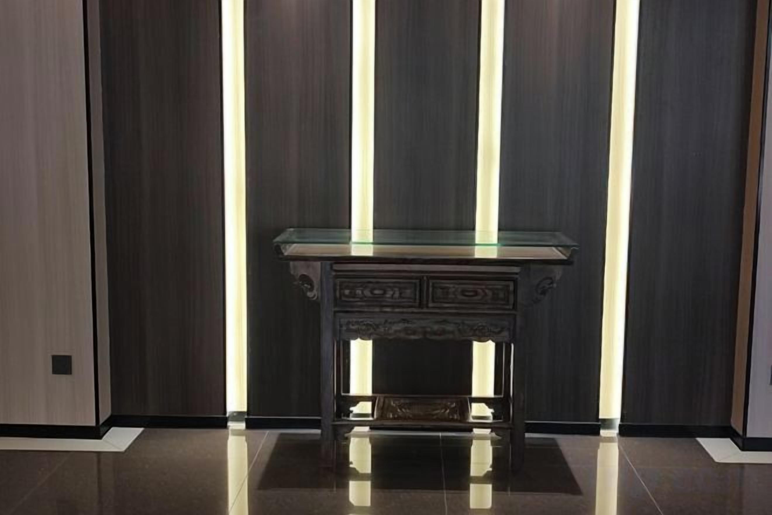 A dark wooden room with a glass-top table and a light fixture.