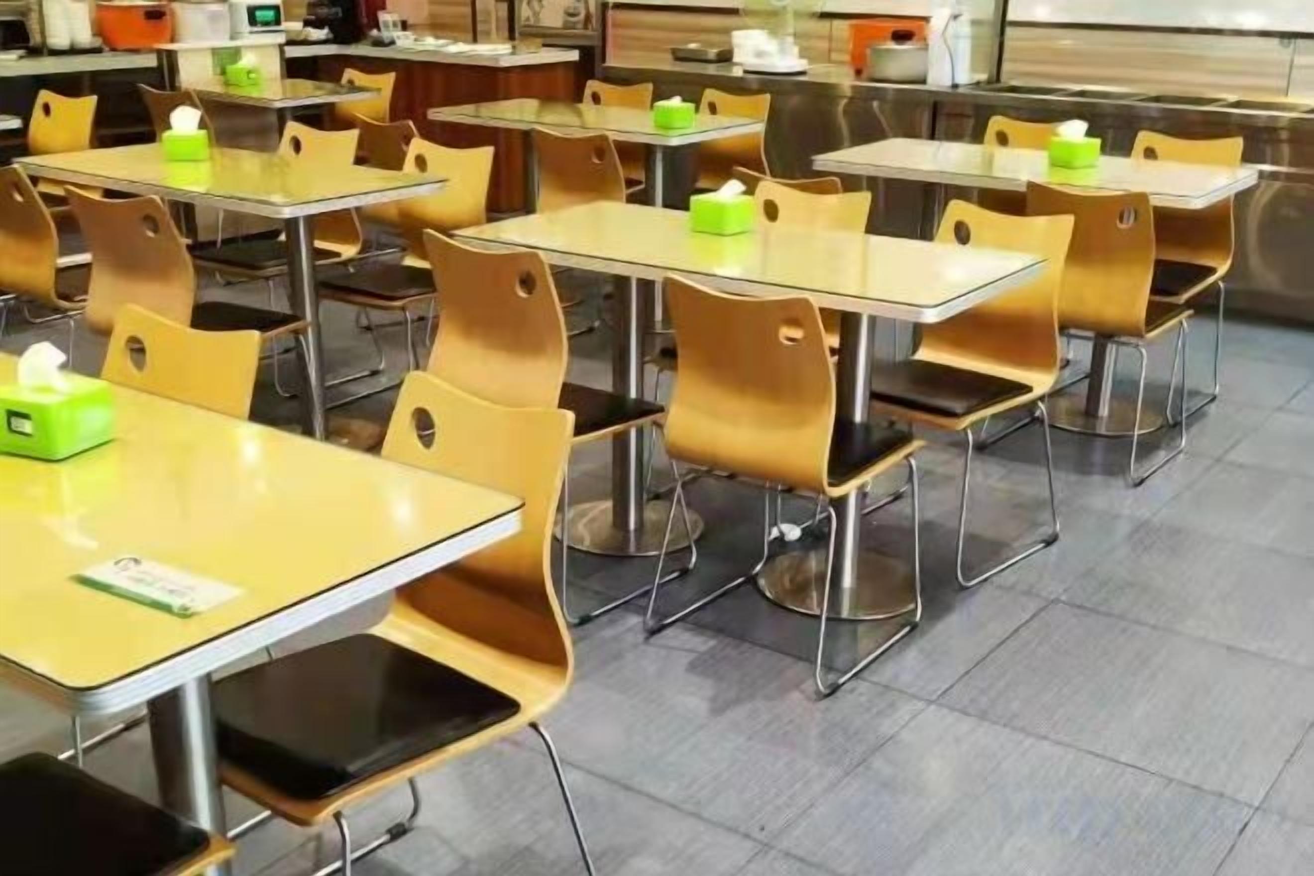 A cafeteria with multiple tables and chairs, some with tissues.