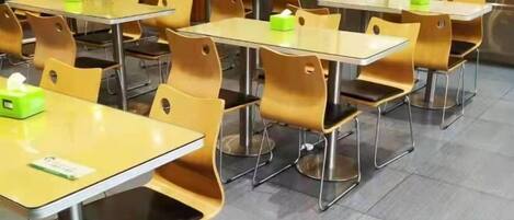 A cafeteria with multiple tables and chairs, some with tissues.