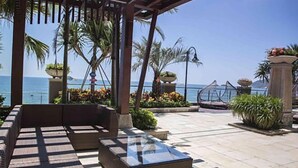 An outdoor seating area with a glass-top table, wicker furniture, and potted plants. - Double Moon Bay Beach Five Star Resort Apartment (Huidong)