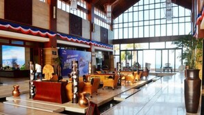 A spacious lobby with a high ceiling, large windows, and a reception area with a counter and seating. - Double Moon Bay Beach Five Star Resort Apartment (Huidong)