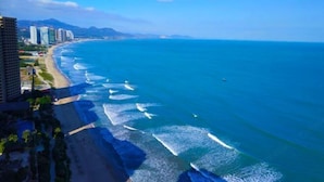 A coastal cityscape with a beach, high-rise buildings, and a clear blue sky. - Double Moon Bay Beach Five Star Resort Apartment (Huidong)