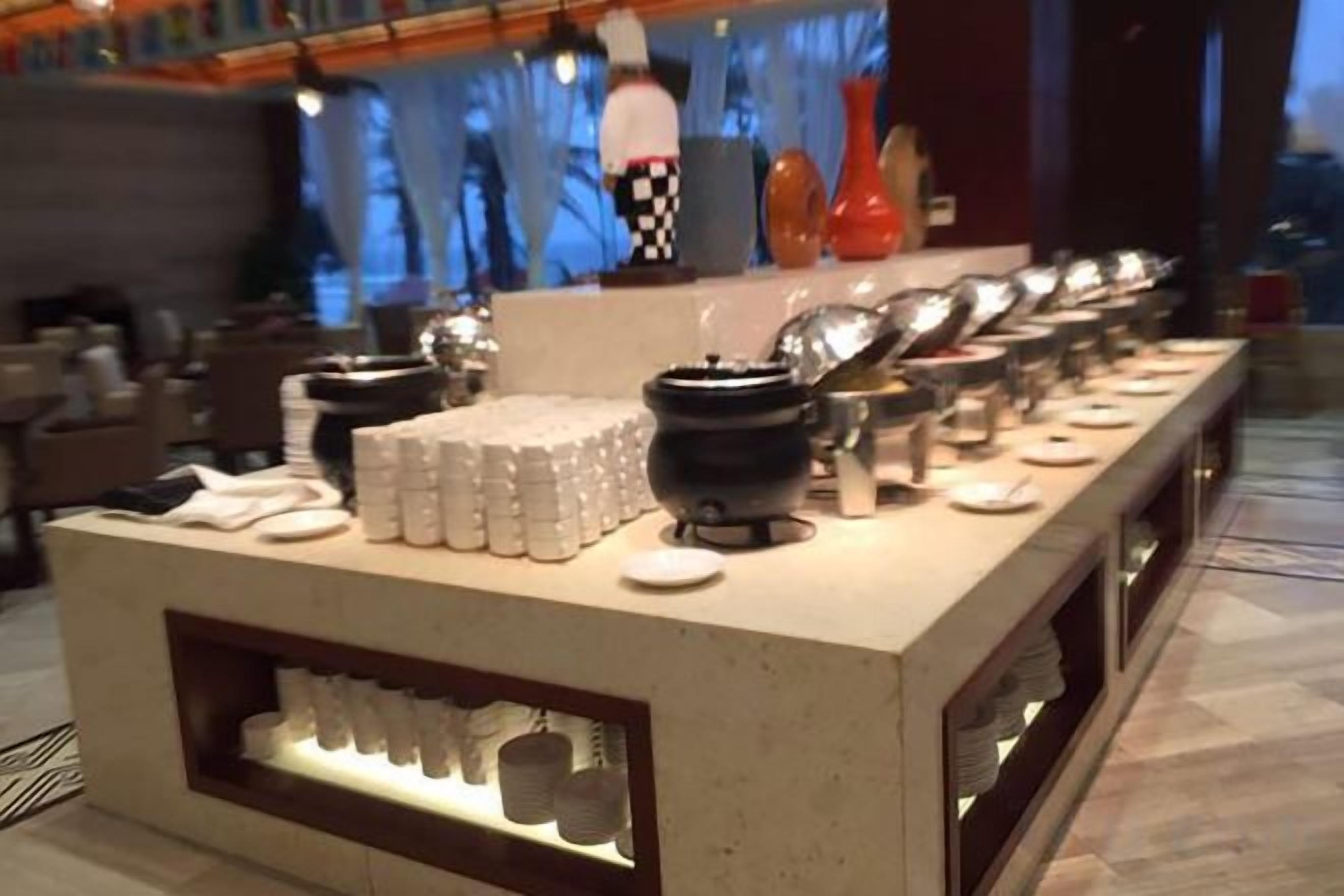 A buffet setup with various food containers and utensils.