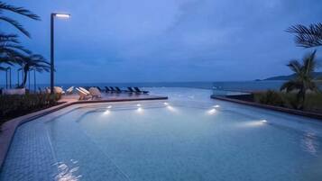 A swimming pool with lounge chairs and a view of the sea.