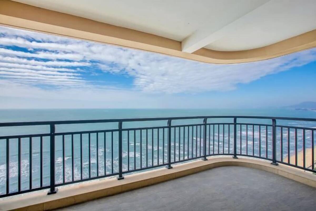 A balcony with a curved railing overlooking a coastal view.