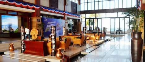 A spacious lobby with a reception desk, seating area, and large windows.