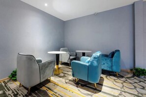A modern lounge area with seating and tables, carpeted flooring, and a ceiling light fixture. - Allston Light Hotel (Xiamen Gaoqi Airport & Wuyuan Bay) (Xiamen)