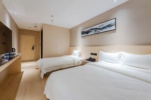 Ein Hotelzimmer mit zwei Betten, einem Schreibtisch mit Kaffeemaschine, einem Bild an der Wand und einer Tür zu einem anderen Raum.