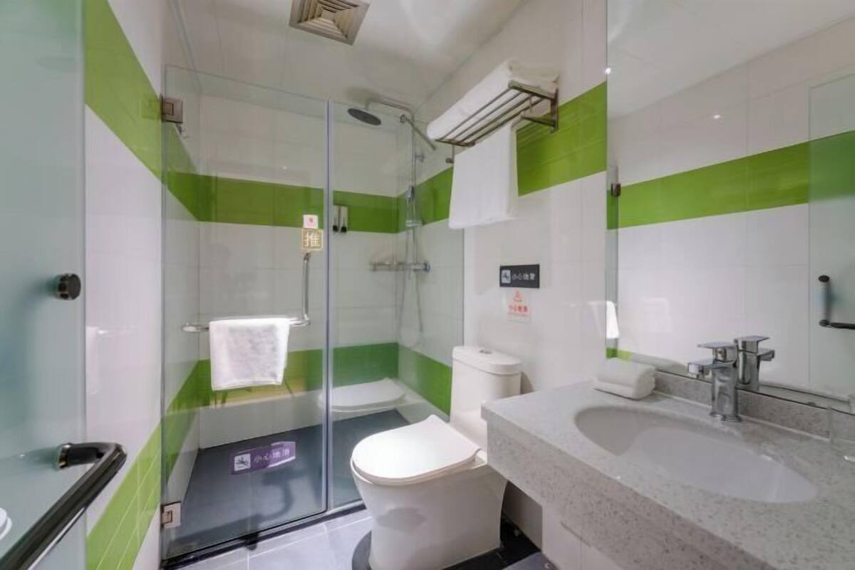 Une salle de bain moderne avec une douche à parois de verre, des toilettes blanches et un lavabo avec un miroir.
