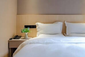 Ein Hotelzimmer mit einem Bett, einem Nachttisch mit Telefon und einer kleinen Pflanze.