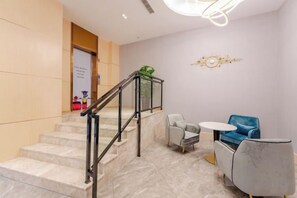 A hotel lobby with marble stairs, a reception desk, and a seating area with a blue chair and a small table. - Allston Light Hotel (Xiamen Gaoqi Airport & Wuyuan Bay) (Xiamen)
