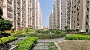 Un quartier résidentiel composé d’immeubles d’habitation à étages élevés, d’un jardin paysager central et d’une allée piétonne dallée.