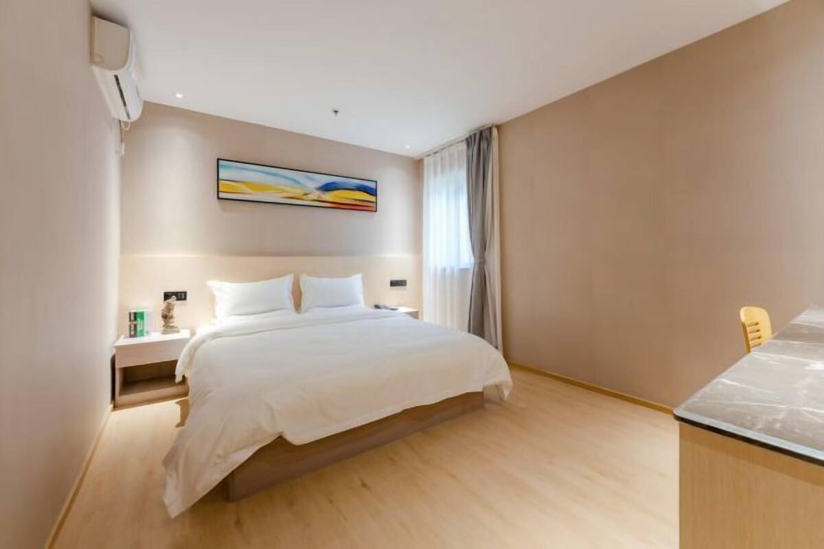 Une chambre d’hôtel avec un lit, des tables de chevet, un bureau et un tableau au mur.