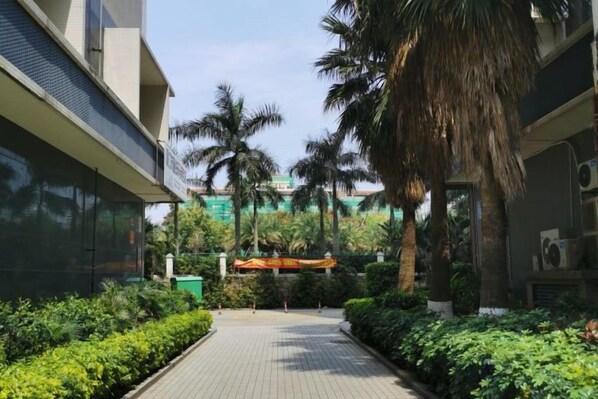 A pathway flanked by lush greenery and palm trees, leading to a building with a modern design. - Allston Light Hotel (Xiamen Gaoqi Airport & Wuyuan Bay) (Xiamen)